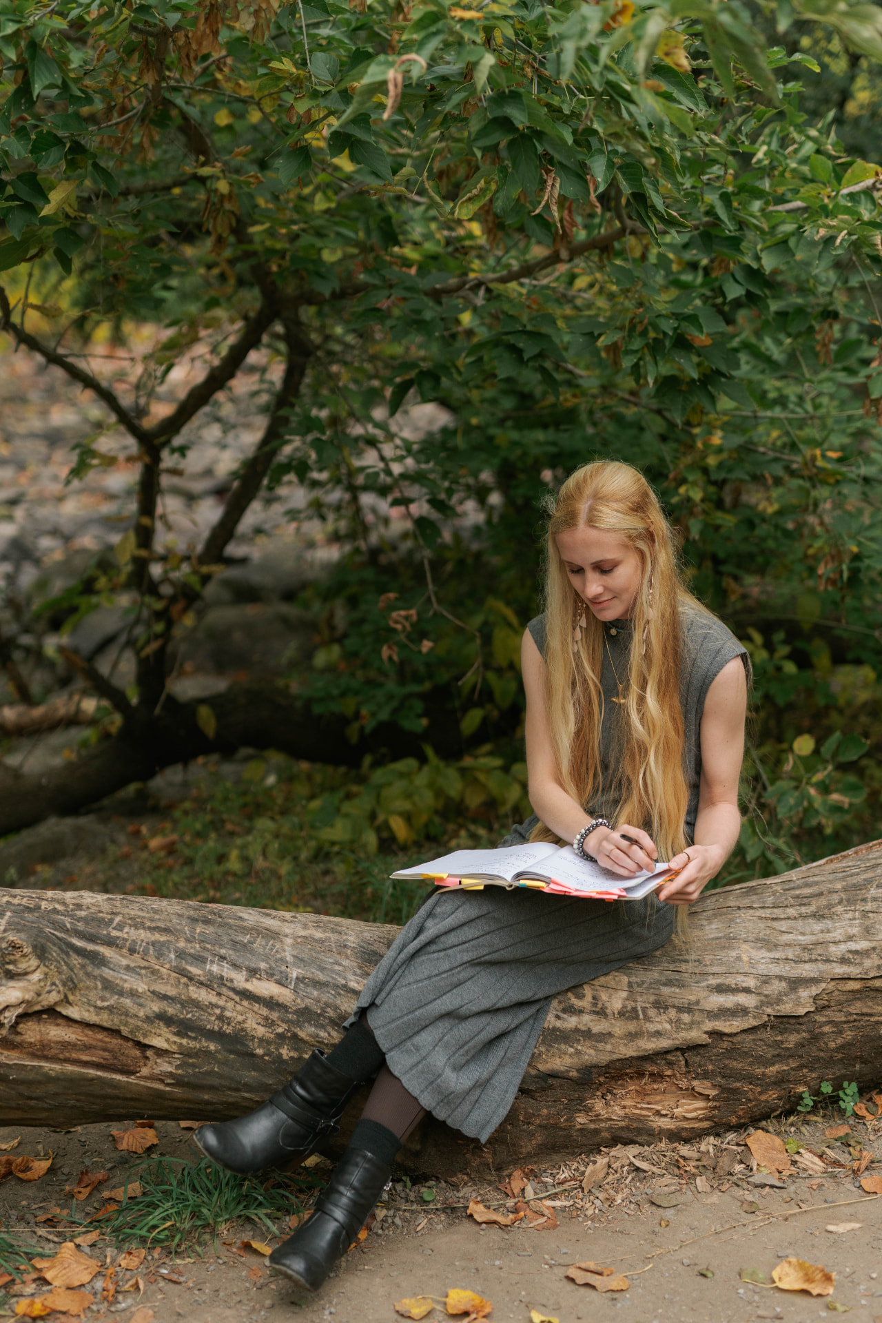 Sarah Cushing writing in a notebook on a fallen log