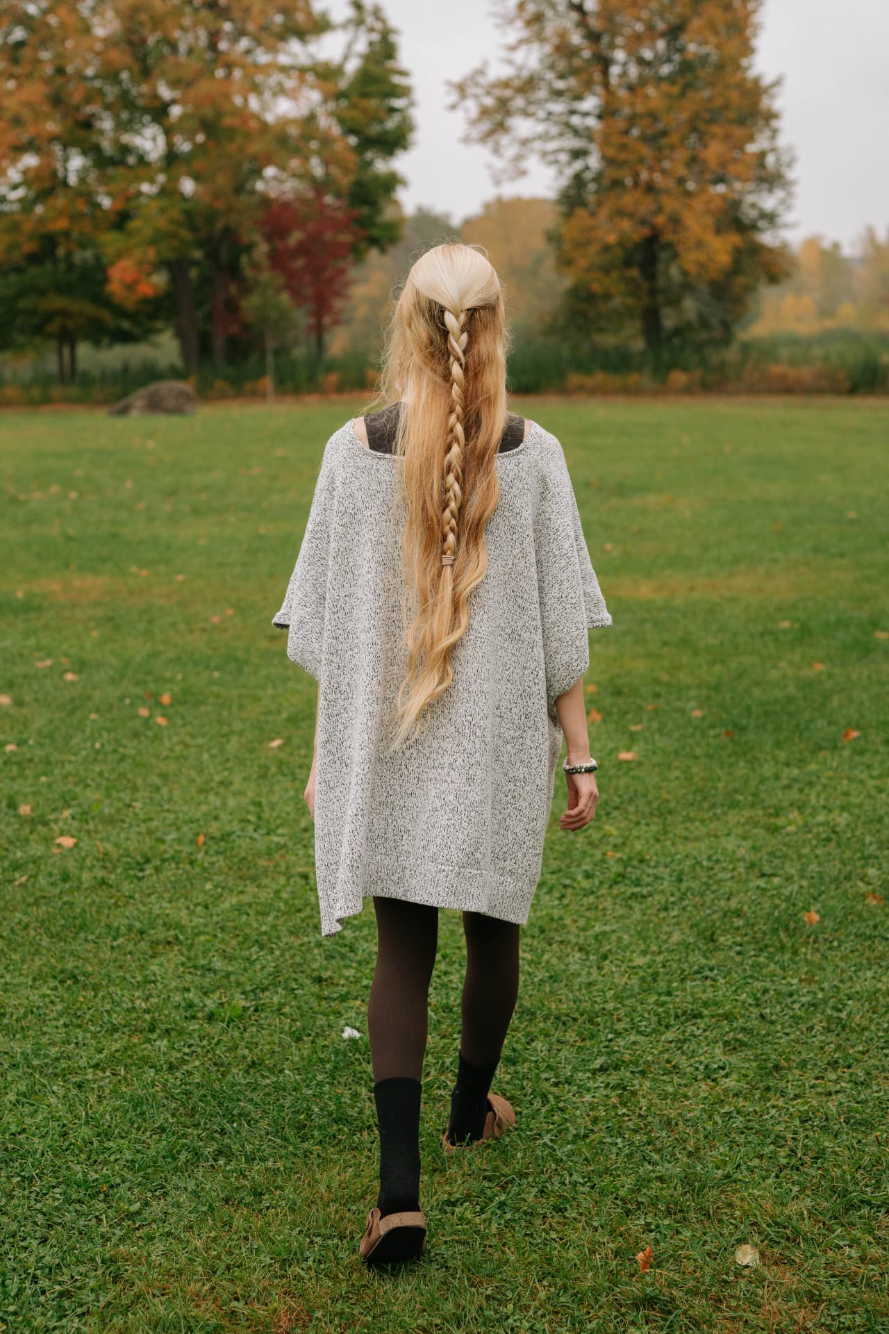 Sarah Cushing walking across a field toward autumn trees
