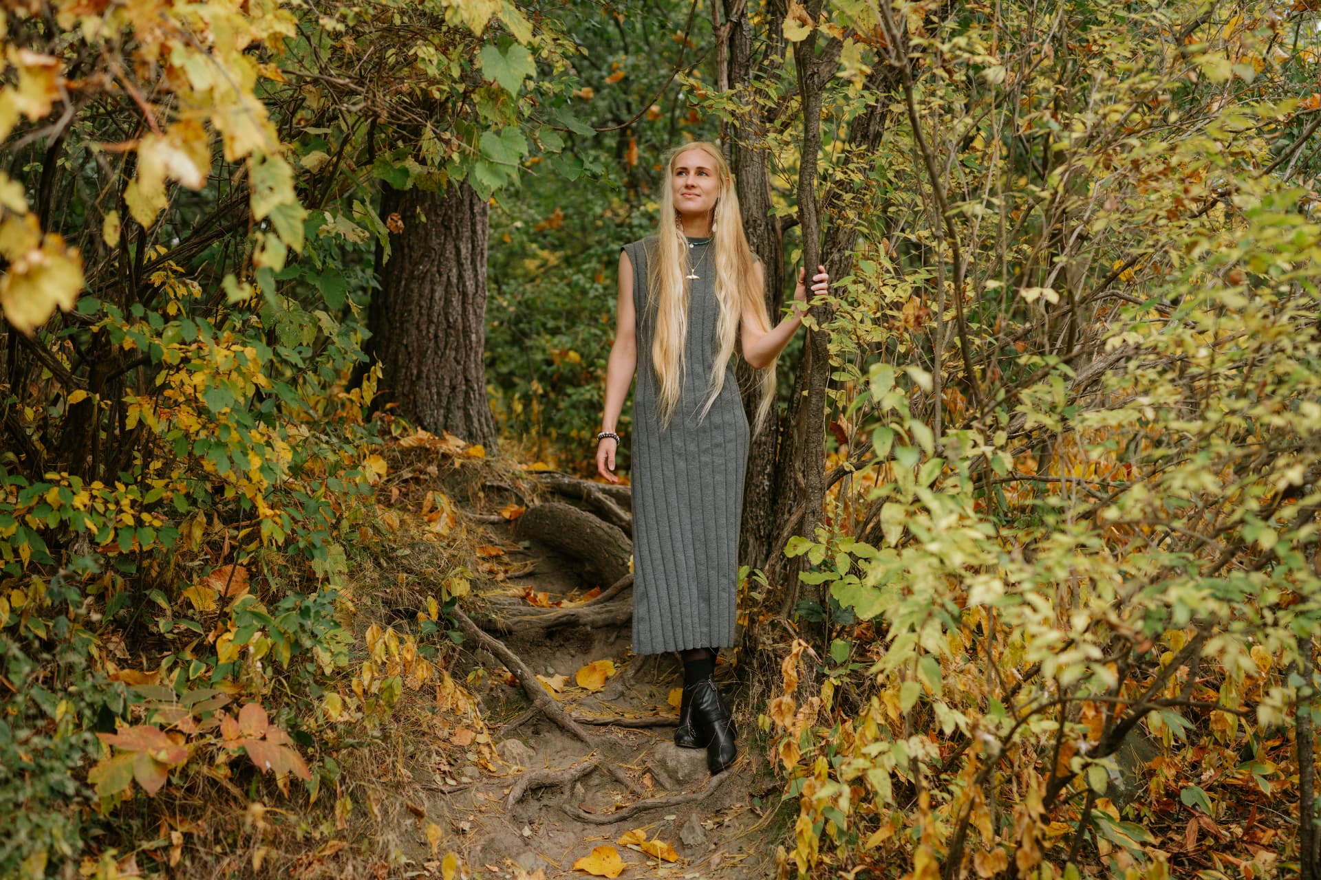 Sarah standing among trees and roots in the forest